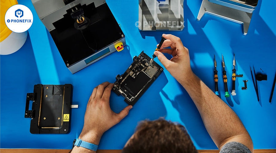 Technician repairing smartphone with precision tools and repair machines on a blue workbench