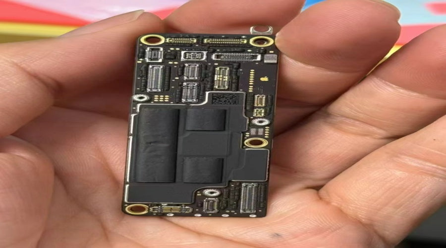 Hand holding a mobile phone motherboard with chips and connectors visible