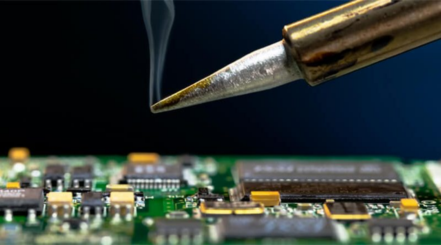 Close-up of soldering iron repairing a mobile phone circuit board with visible microchips