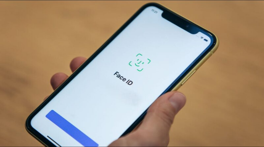 Hand holding smartphone displaying Face ID setup screen, mobile phone repair concept