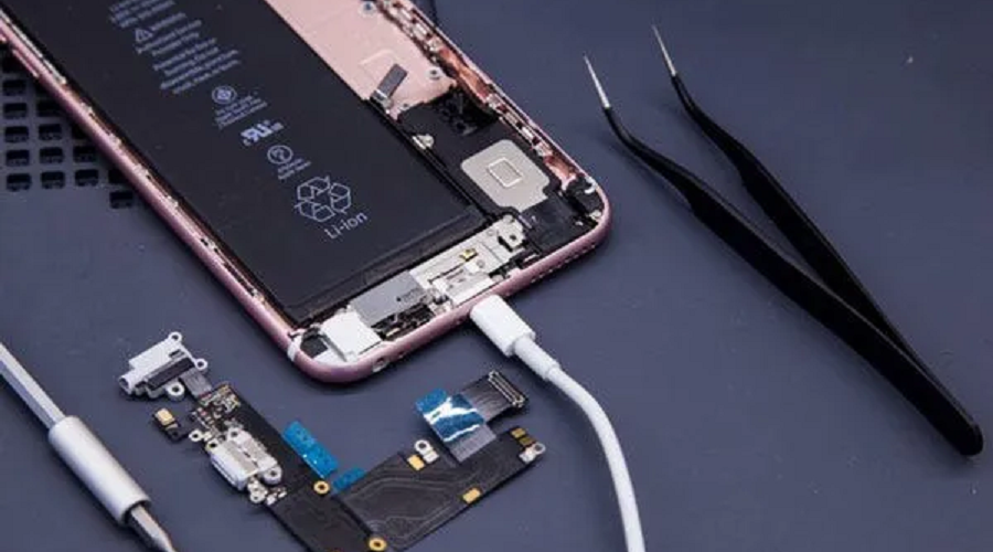 iPhone charging port repair with opened phone, replacement parts, tweezers, and charging cable