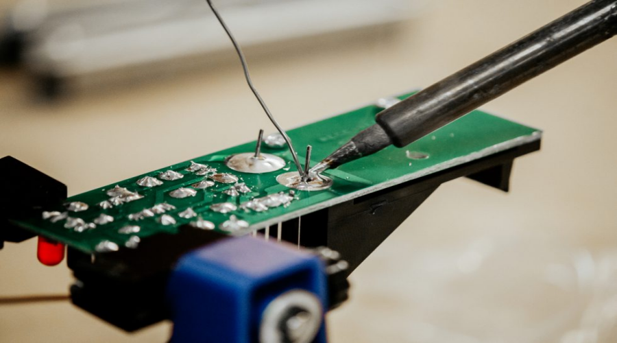 Soldering iron working on electronic circuit board for phone repair