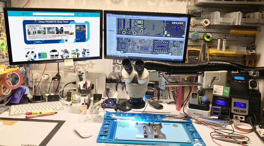 Mobile phone repair workstation with microscope, dual monitors, and repair tools.