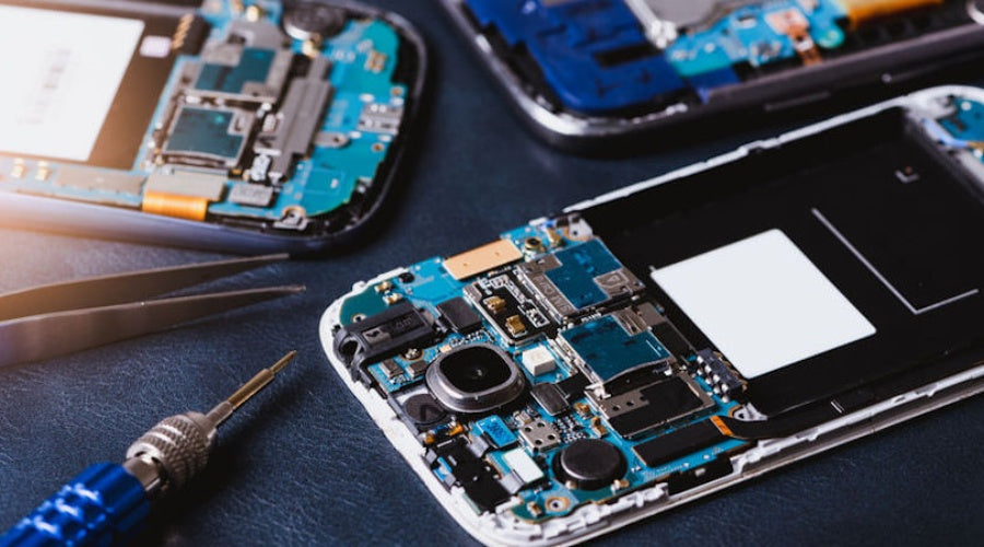 Disassembled smartphones with circuit boards and precision repair tools on a workbench