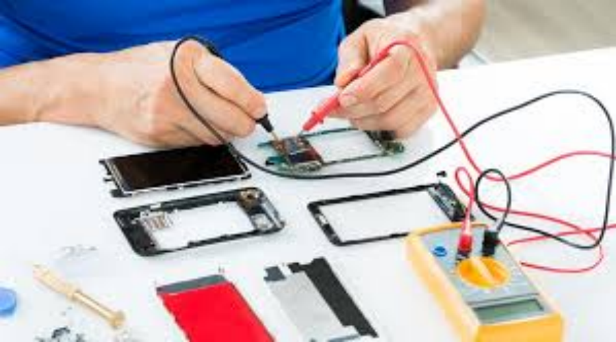 Technician repairing smartphone motherboard using multimeter and soldering tools on desk