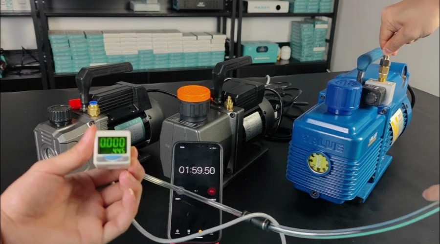 Three vacuum pumps being tested with a digital gauge and a timer on a workbench