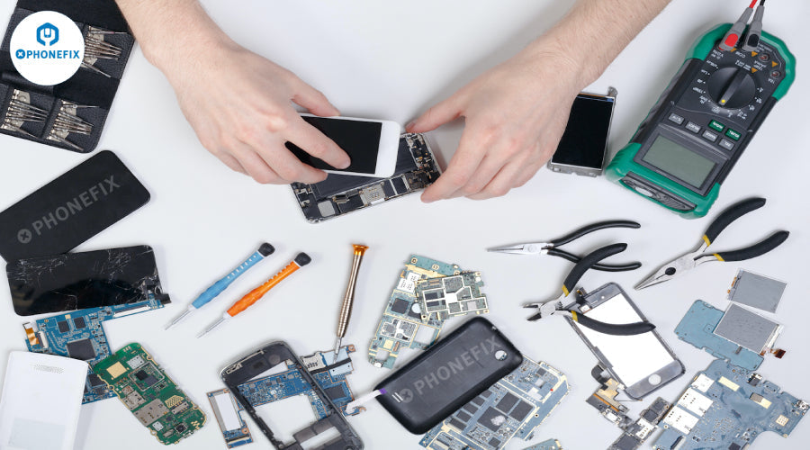 Hands repairing smartphone with repair tools, mobile phone parts, and circuit boards on white table.