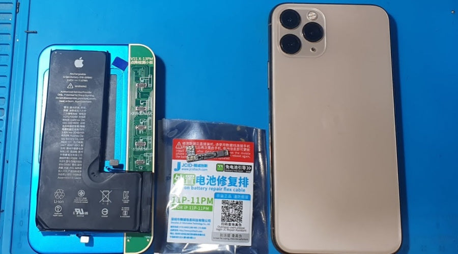 iPhone battery and logic board on repair mat next to iPhone and battery repair flex cable kit