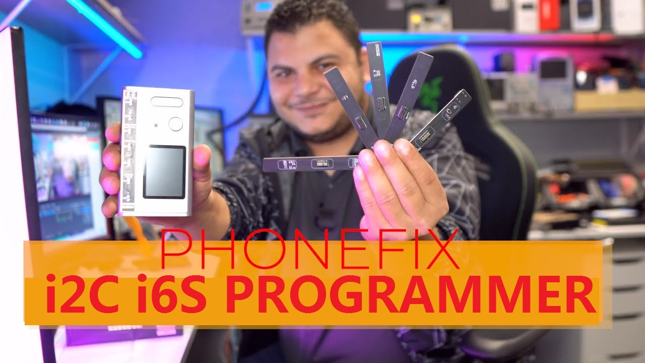 Man in electronics workshop holding i2C i6S programmer and adapters for phone repair.